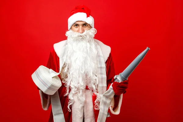 Weihnachtsmann in Weihnachtsmannkleidung mit Feuerwehrschlauch gegen i — Stockfoto