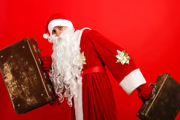 Santa Claus de pie con bolsa de viaje con toques en el fondo rojo —  Fotos de Stock