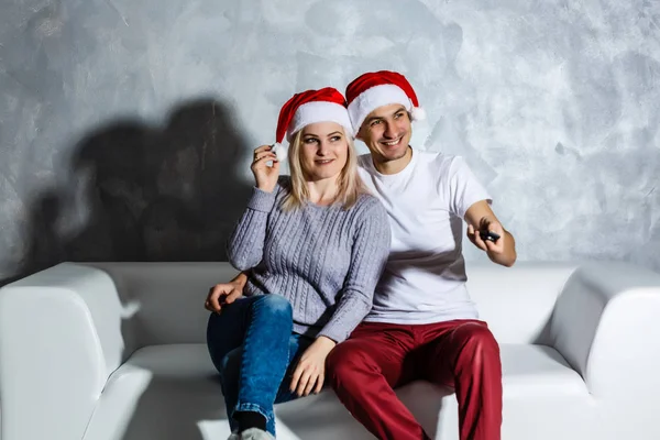 Jeune Couple Heureux Dans Des Chapeaux Noël Regarder Télévision Maison — Photo