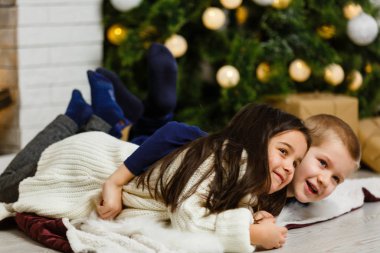 Mutlu küçük çocuklar Noel ağacının altında poz veriyor