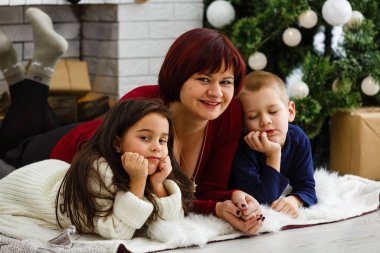 Genç anne ve iki küçük kızı Noel arifesinde sıcak, karanlık bir oturma odasında ellerinde mumlarla şöminenin başında oturuyorlar. 