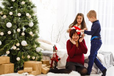 Çocuklar ve anne yeni yıl dekorasyonlarıyla stüdyoda poz veriyorlar. 