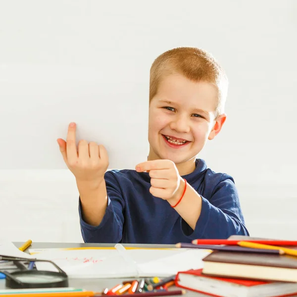 テーブルの上のスマートで陽気で 幸せで 小さい 男の子 学童は問題と教訓を解決する — ストック写真