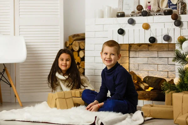 暖炉でクリスマスの前夜に家族 ギフトボックス付きクリスマスツリーの下の子供たち 伝統的な暖炉のある装飾されたリビングルーム 家で居心地の良い暖かい冬の夜 — ストック写真