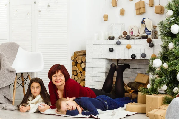 若い母親と彼女の二人の小さな娘によって座って暖炉を保持キャンドルで居心地の良い暗いリビングルームでクリスマスの前夜 — ストック写真