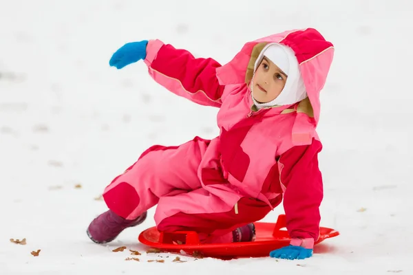 Een gelukkig klein kind met haar handen omhoog is genieten van sleeën in w — Stockfoto