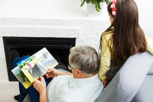 Kleindochter en grootvader kijken samen naar foto 's in een foto — Stockfoto