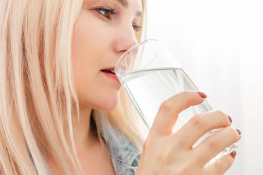 Evdeki kanepede oturan su içen kız.