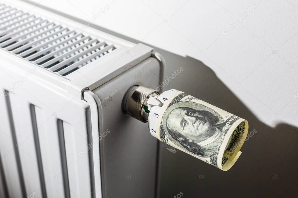 Heating thermostat with money, one dollar, expensive heating costs concept