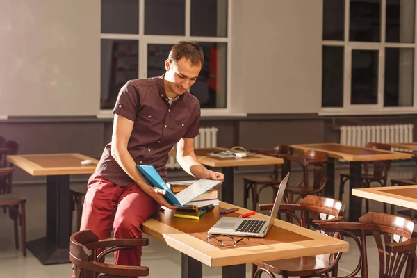 Young male teacher holding a book in a maths classroom