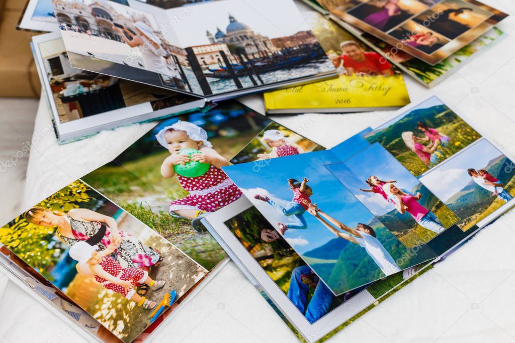 Photo albums with photos lying on white surface