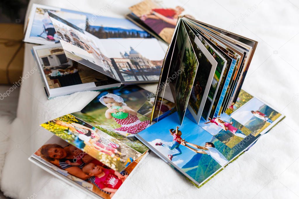 Photo albums with photos lying on white surface