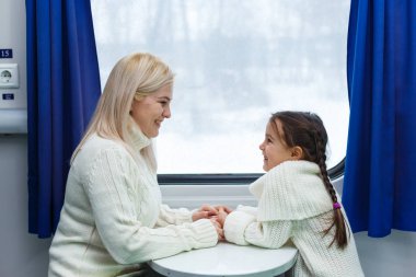 Anne ve kızı trenle seyahat ediyorlar.