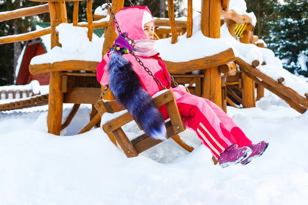 迷人的小女孩 在秋千上在下雪的冬天 — 图库照片