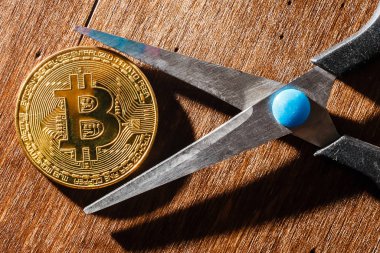 Siyah arkaplanda makas ile resmin üzerinde ana nesne olarak altın bir bitcoin