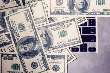 Yüz dolarlık banknotlar laptop klavye üzerinde yalan closeup görünümü.
