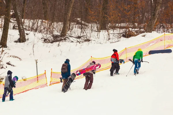 Os snowboarders alegres, com snowboards em suas mãos, vão acima do m — Fotografia de Stock