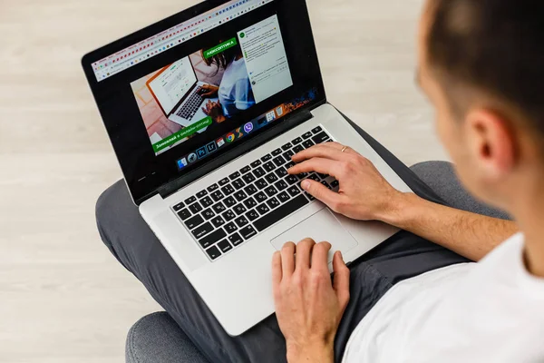 Evdeki fotokopi odasında laptopta çalışan genç adam.