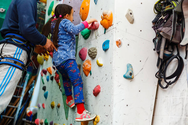 little girl climber in leisure park with climbing wall 