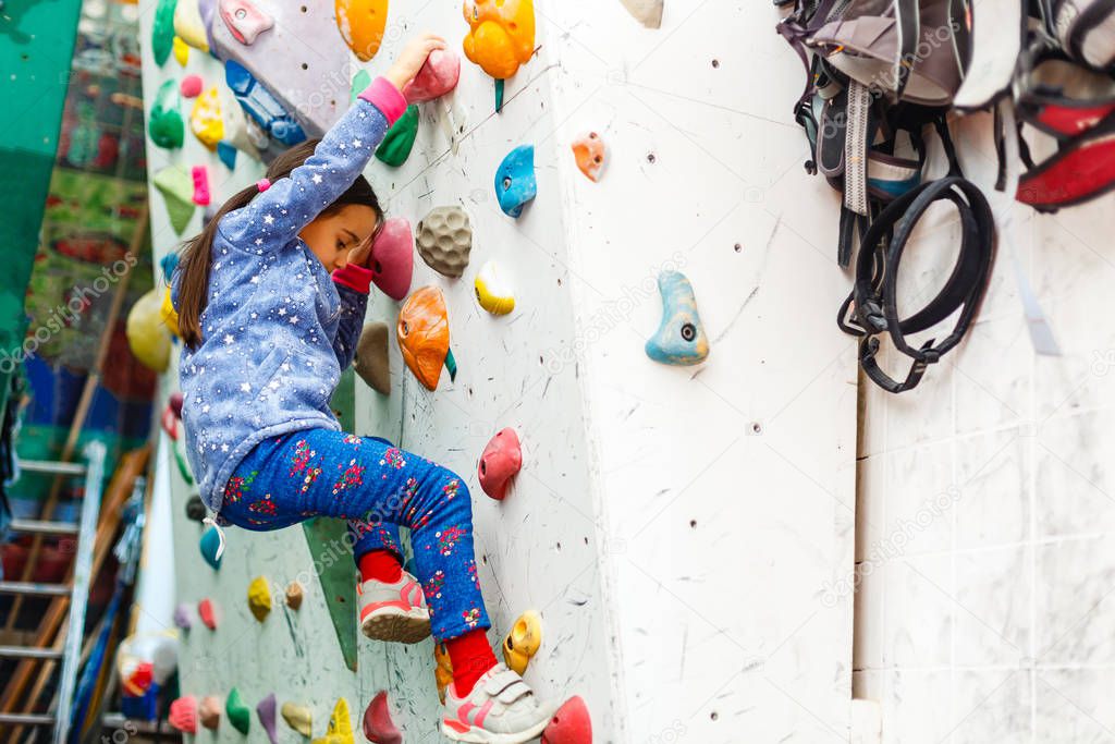little girl climber in leisure park with climbing wall 