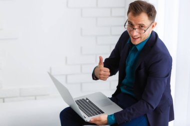 Ofiste dizüstü bilgisayarla çalışan yakışıklı iş adamı.