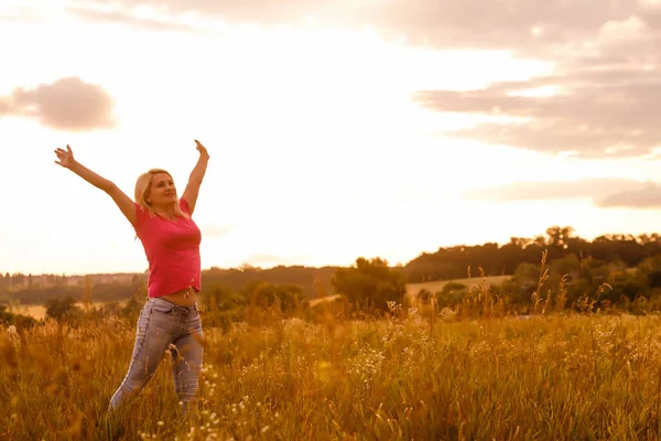 女性シルエット待っていますのために夏の太陽上の牧草地 — ストック写真
