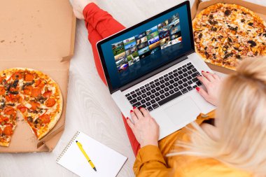 Koltuğun yanında oturan ve dizüstü bilgisayarda video izleyen genç bir kadın.