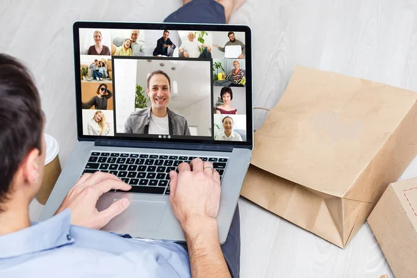 Back view of young man using headset and laptop and having videoconference at home — Stock Photo, Image