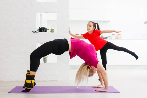 Mother and daughter doing exercises on mat at home. — Stock Photo, Image
