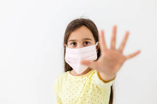 가벼운 배경에 일회용 마스크를 쓴 어린 소녀. 코로나 바이러스 유행병 예방 — 스톡 사진