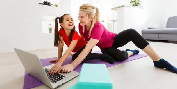 Madre e figlia che fanno esercizi di yoga sul tappeto a casa. — Foto Stock