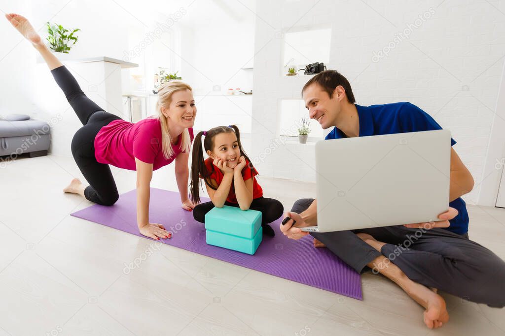 Quarantine at home. little girl doing yoga olnline on a laptop during self isolation quarantine