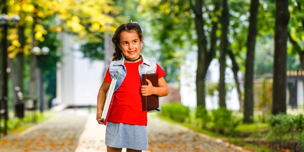 Kislány besétál az iskolába reggel hátizsákkal a meleg napsütésben. Oktatási koncepció. — Stock Fotó