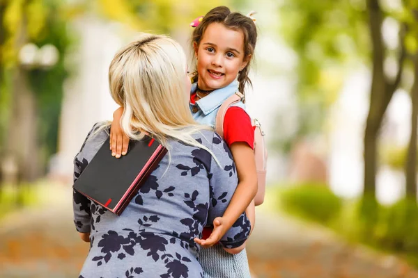 Primer día en la escuela. madre conduce a una niña pequeña de la escuela en primer grado — Foto de Stock