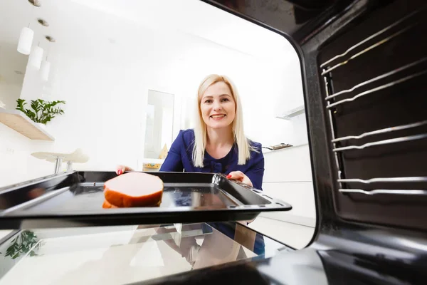 Porträt einer jungen Frau, die in der Küche Essen zubereitet. Junge Hausfrau hält frisch gebackenes Fleisch — Stockfoto