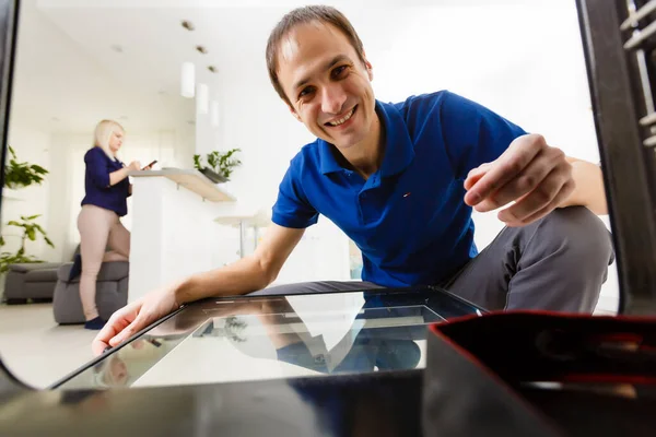 Hombre viendo algo cocinar en el horno en su cocina inclinándose hacia abajo para mirar dentro de la estufa para comprobar si está listo — Foto de Stock