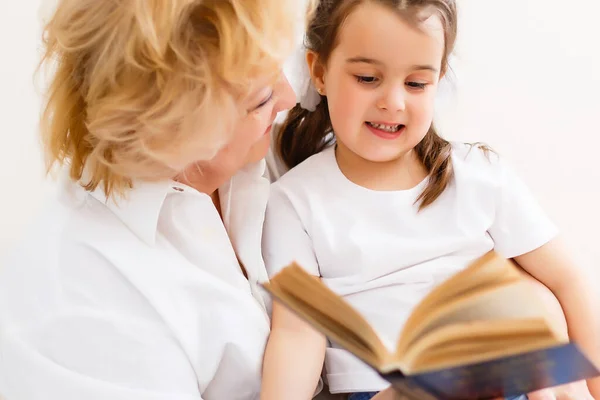 Liten flicka med mormor läser intressant bok — Stockfoto