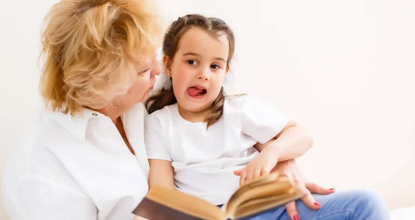 La nonna legge un racconto alla sua nipotina. Tempo libero di lettura della famiglia. Tempo di qualità. Happy Family si diverte a giocare a casa. — Foto Stock
