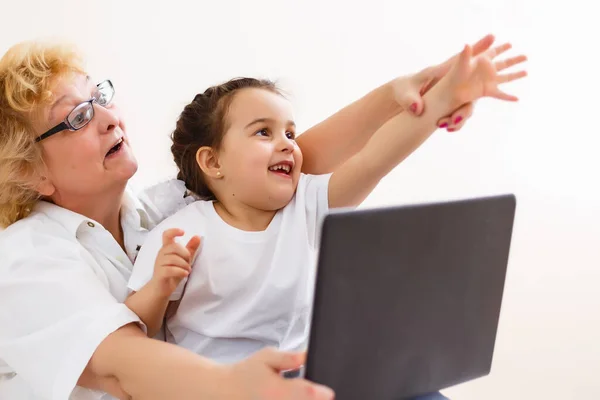 Ragazza intelligente nipote sedersi sul divano a fare shopping online con eccitata nonna anziana, nipote adolescente e sorridente nonna acquistare su internet navigazione laptop relax a casa insieme — Foto Stock