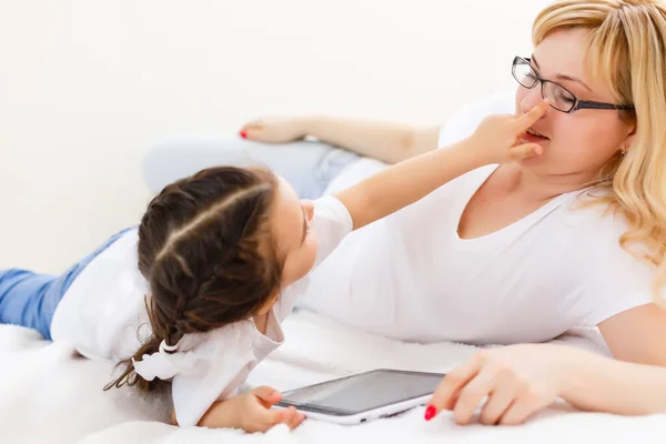 Felice famiglia mamma e figlia bambino utilizzando tablet digitale seduto sul divano, sorridente madre genitore con bambino ragazza tenendo tablet guardando lo schermo fare shopping online fare videochiamata guardare cartoni animati — Foto Stock