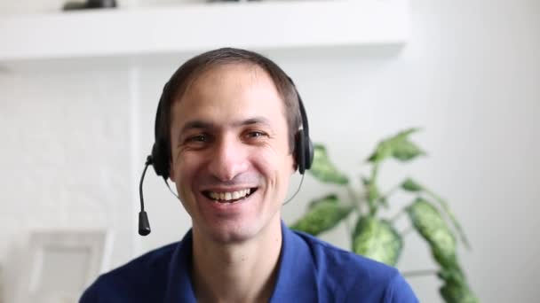 Un hombre con una camisa azul y sonriendo a la cámara en línea — Vídeos de Stock