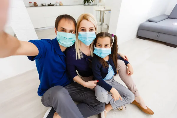 Three people Caucasian family with dad, mom and daughter staying at home wearing facial masks, portrait