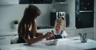 Anne ve kızı mutfakta resim yapıyor. Kızı üzgün ve başarılı olamadığı için ağlıyor. Annem ona güven veriyor. Ebeveynlik kavramı