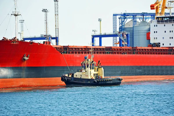 Буксир, помогающий грузовому судну — стоковое фото