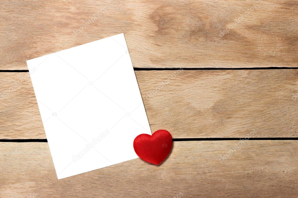 White paper with heart on wood background