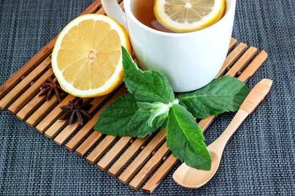 White tea mug with lemon and mint leaves and a wooden spoon — Stock Photo, Image