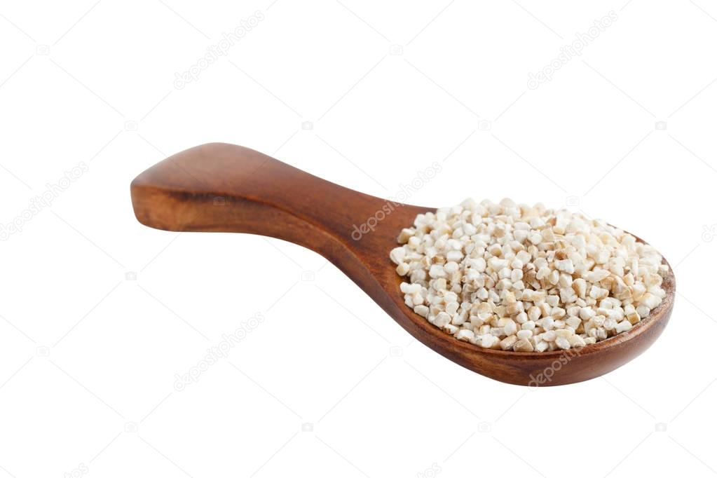 Barley groats on wooden spoon isolated on white background.