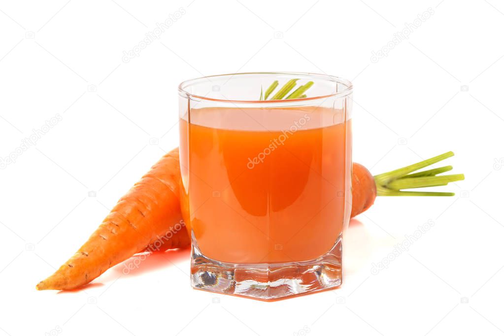 Carrot juice in a transparent glass with carrots from behind
