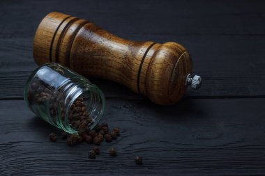 Karabiber ile jar ve siyah ahşap arka planda bir değirmen