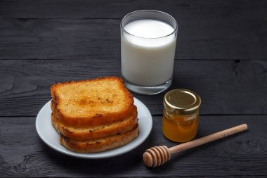 Sütlü tost ve bir kavanoz bal siyah ahşap zemin